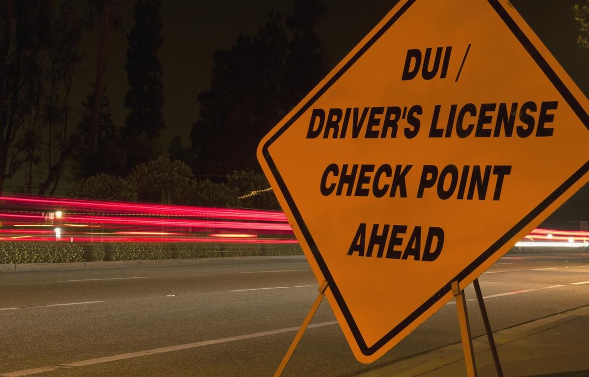 DUI checkpoint sign with blurred car lights at night