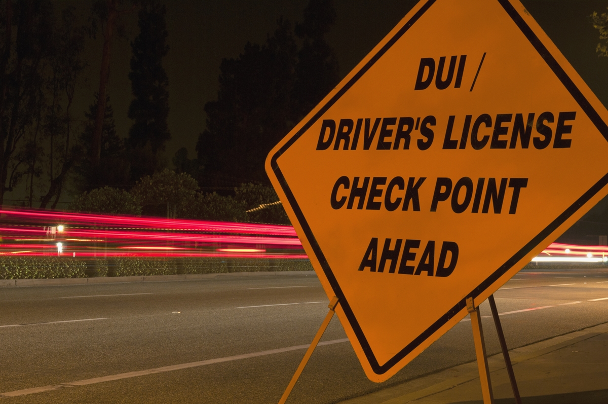 DUI checkpoint sign with blurred car lights at night