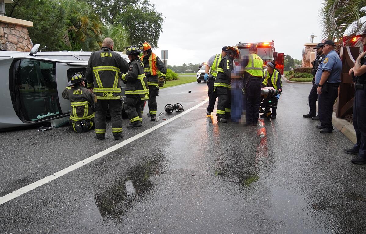 Firefighters and paramedics assist a driver next to an overturned SUV in Ocala.