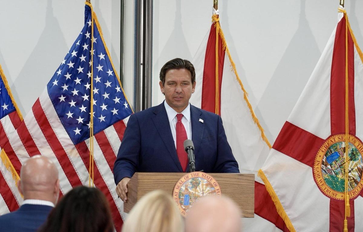 Florida Gov. Ron DeSantis speaks at a podium flanked by American and Florida state flags during a press conference.