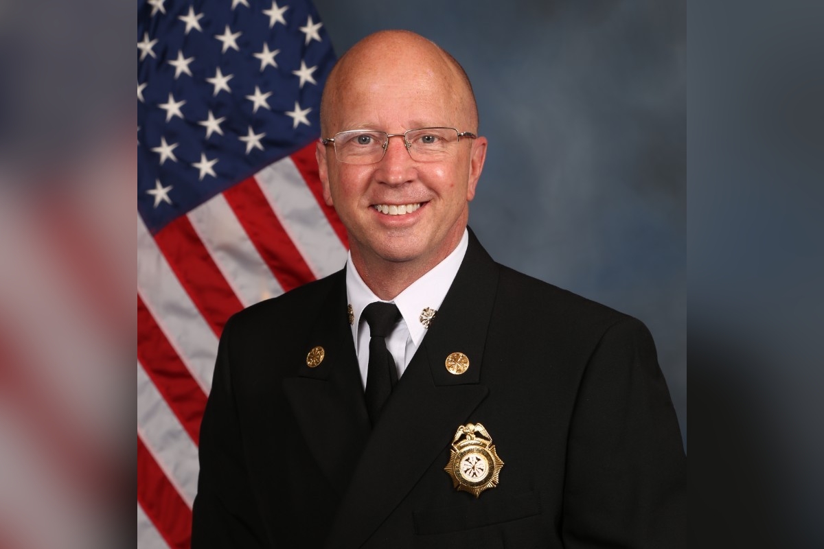 Portrait of Alachua County Fire Rescue Chief Harold Theus in uniform, standing in front of an American flag.