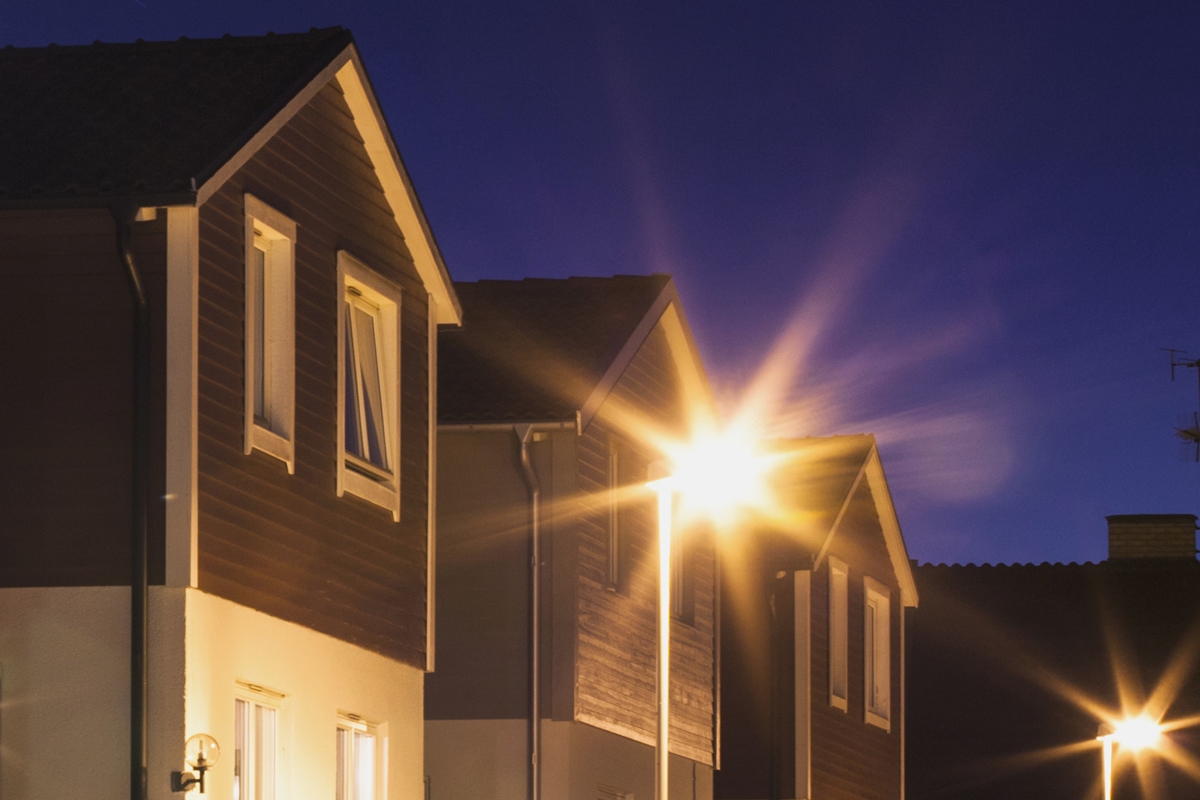 Streetlights shining in a residential neighborhood at dusk.