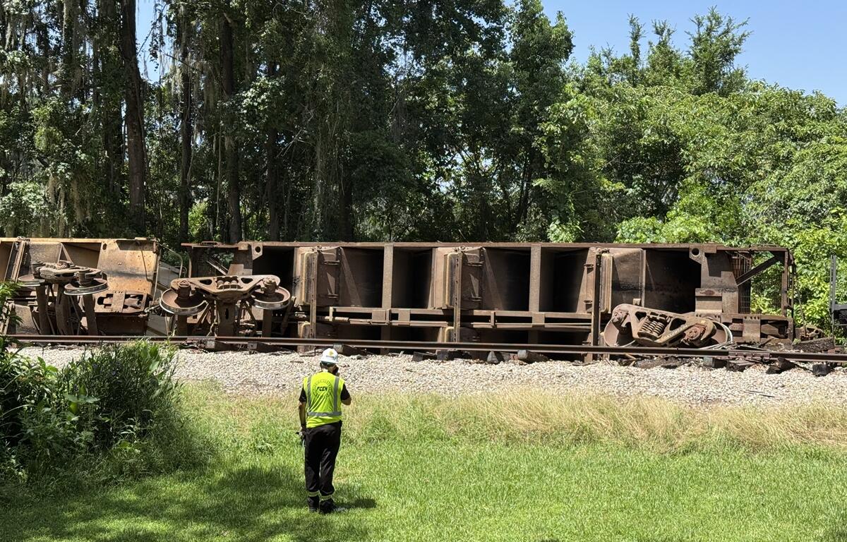 Rail worker stands near overturned train cars following derailment in Ocala.