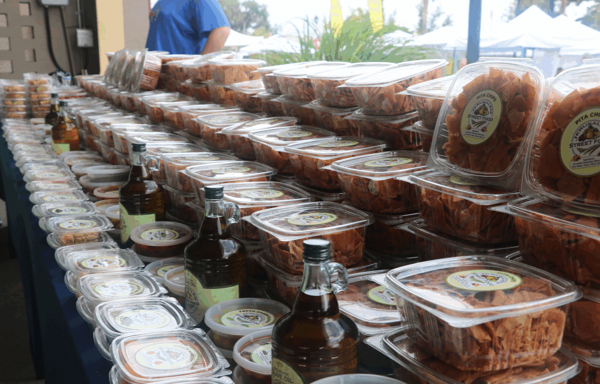 A table stocked with olive oil, packaged pita chips and salsas and hummus.