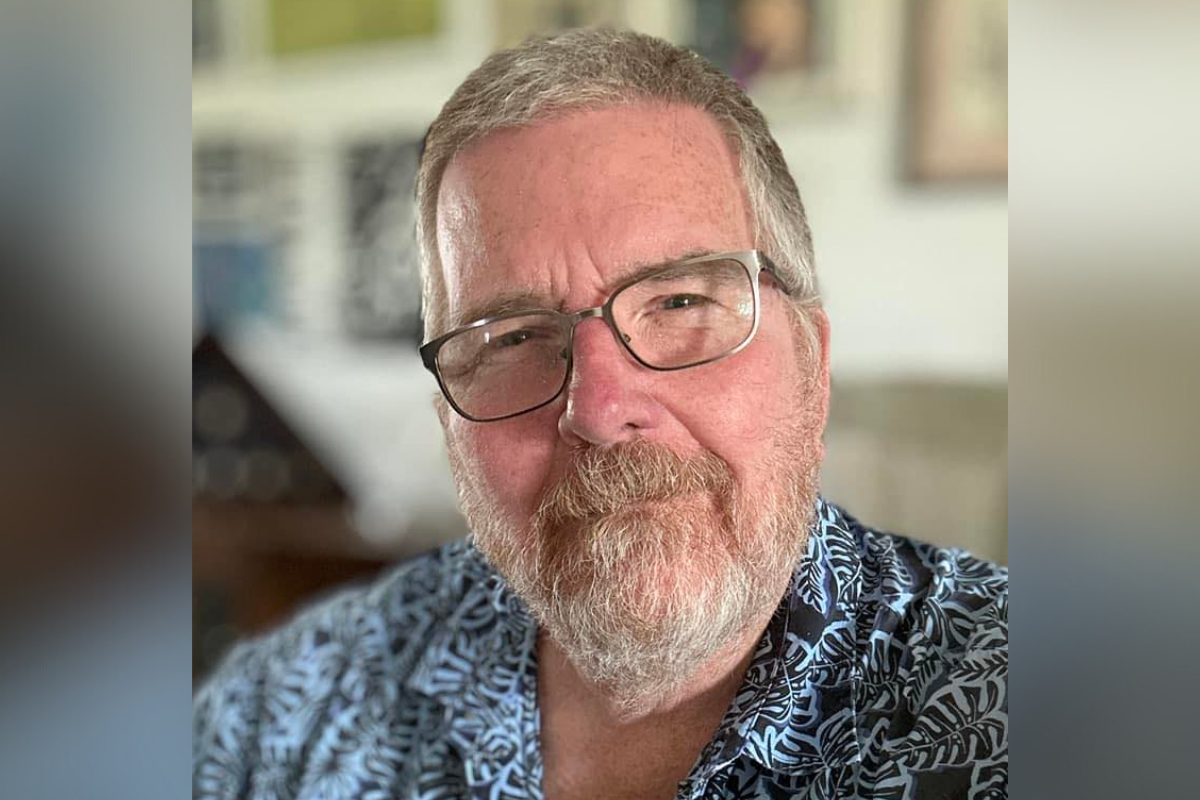 Portrait of Larry Whitler, smiling slightly and wearing glasses and a patterned shirt