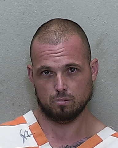 Booking photo of Matthew Quick wearing an orange and white striped jail uniform.