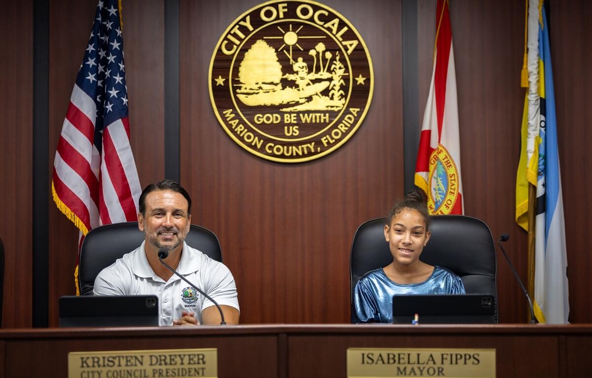 Mayor Ben Marciano and Isabella Fipps seated at the Ocala City Hall dais beneath the city seal.