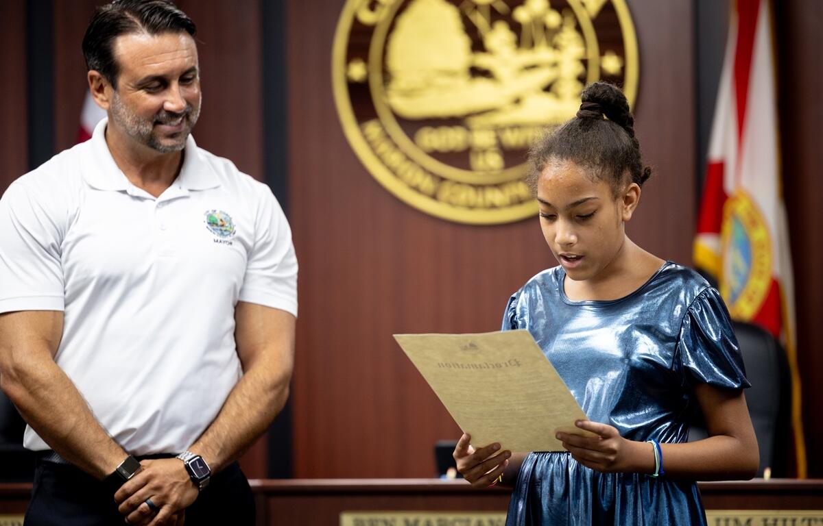 Isabella Fipps reads a proclamation while Mayor Ben Marciano stands beside her at Ocala City Hall.