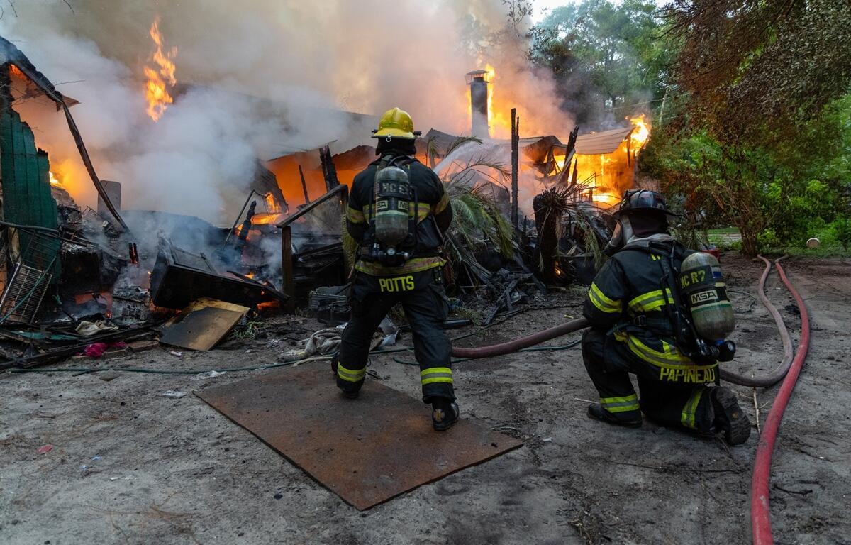 Two firefighters battle flames and heavy smoke as a mobile home burns in Ft. McCoy.