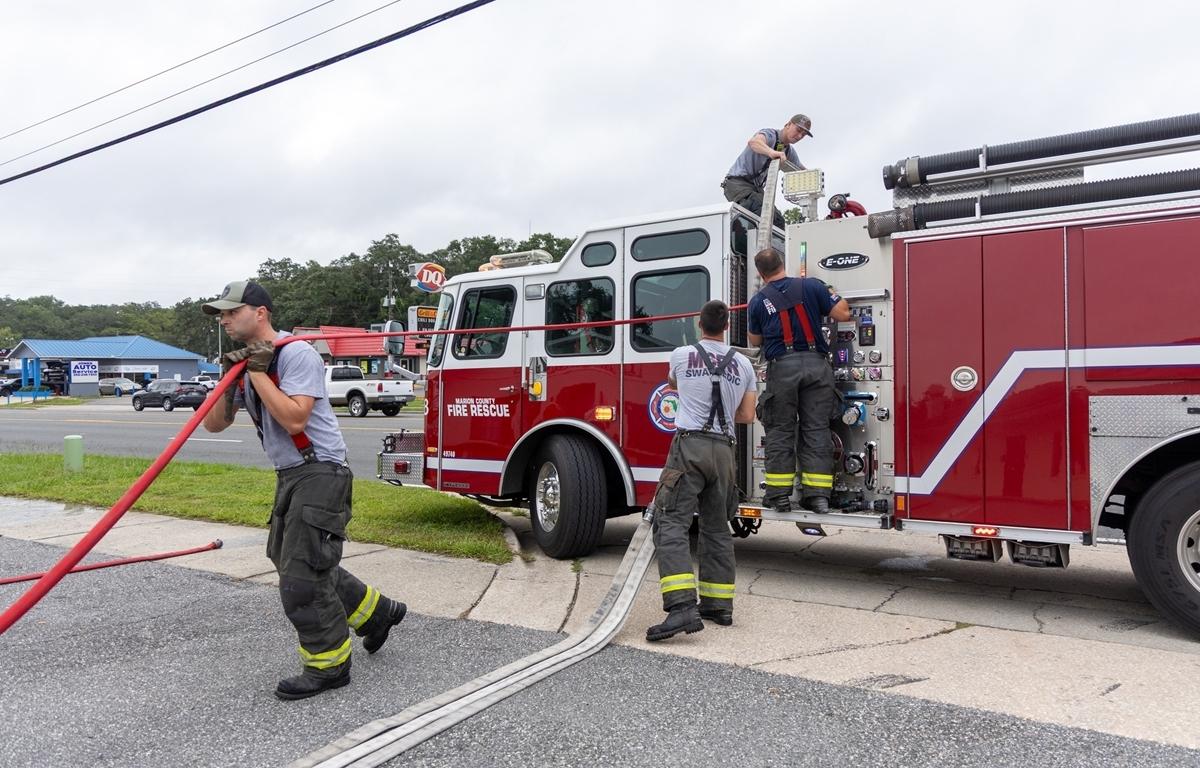 Marion County firefighters manage hoses and equipment beside a fire truck outside a laundromat.