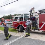 Marion County firefighters manage hoses and equipment beside a fire truck outside a laundromat.