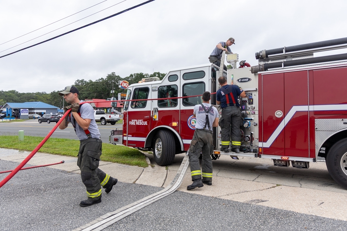 Marion County firefighters manage hoses and equipment beside a fire truck outside a laundromat.