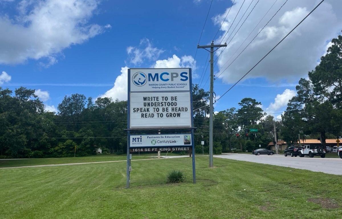 MCPS sign with motivational message on grassy roadside in Ocala under partly cloudy skies.
