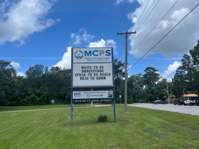 MCPS sign with motivational message on grassy roadside in Ocala under partly cloudy skies.