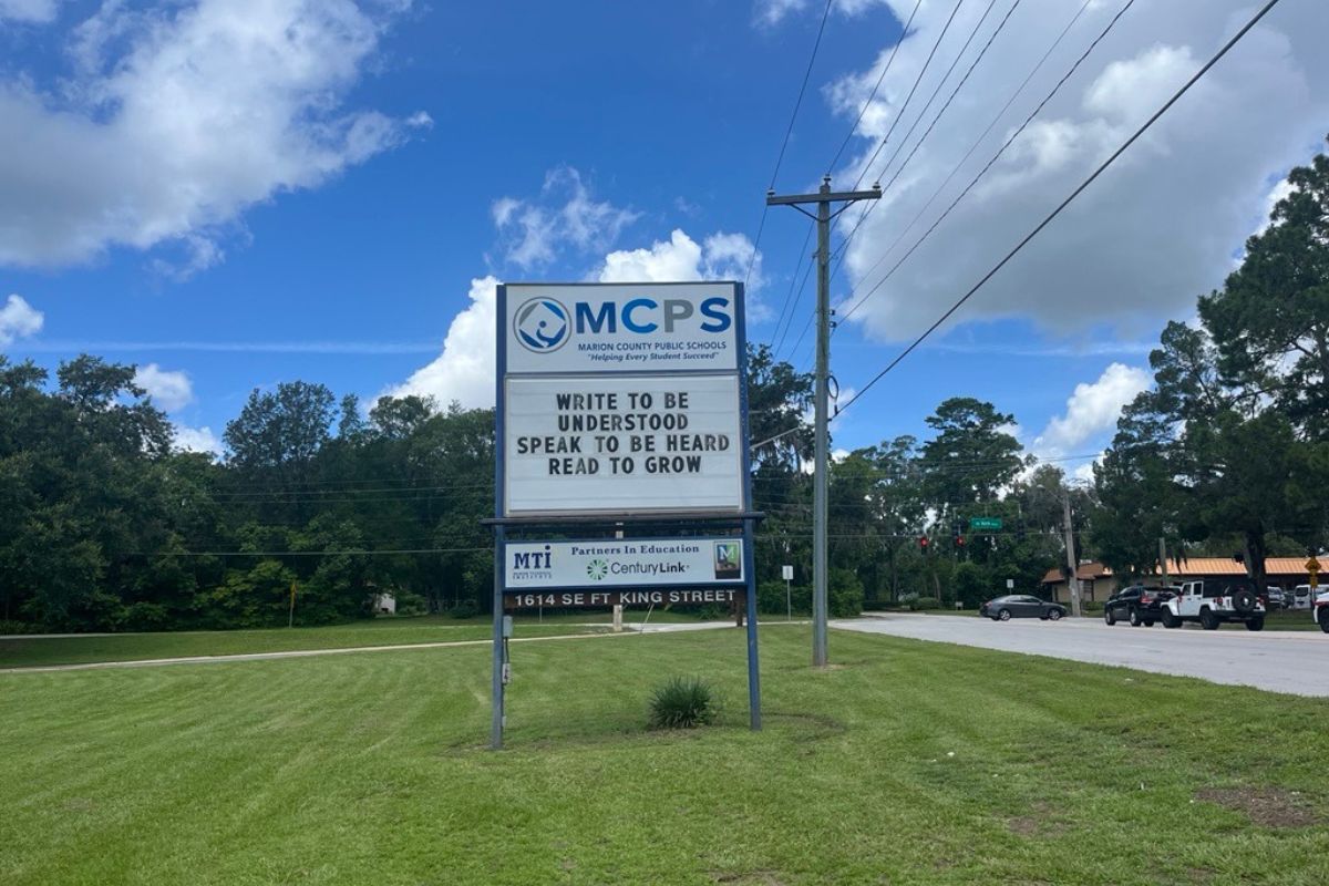 MCPS sign with motivational message on grassy roadside in Ocala under partly cloudy skies.