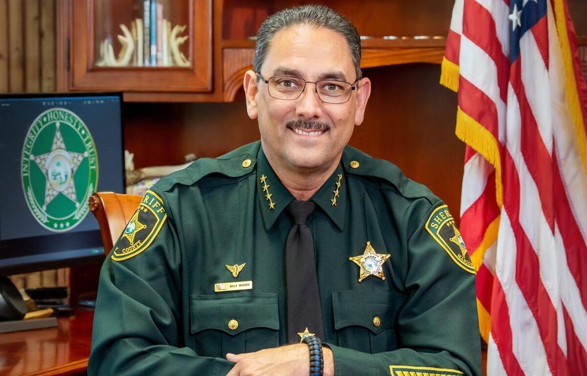 Marion County Sheriff Billy Woods seated at his desk in uniform with American flag