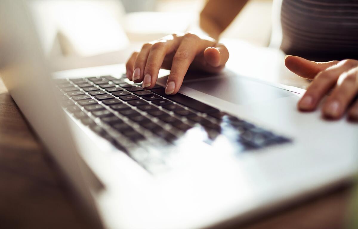 Hands typing on a laptop keyboard during digital media work