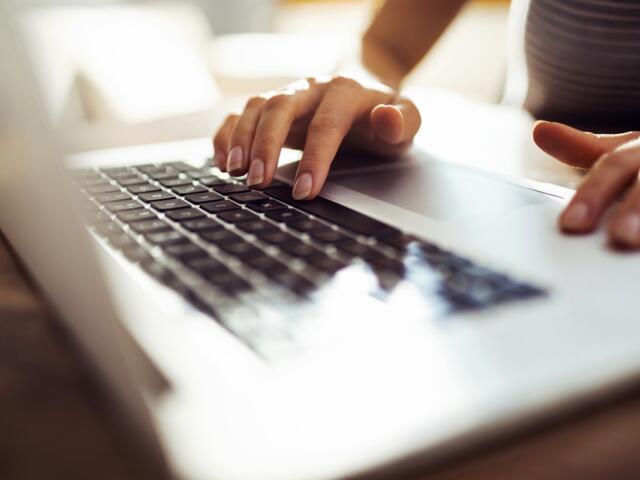 Hands typing on a laptop keyboard during digital media work