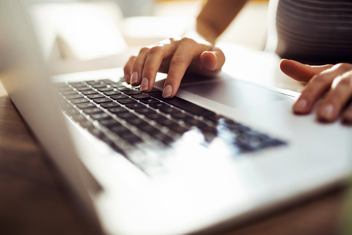 Hands typing on a laptop keyboard during digital media work