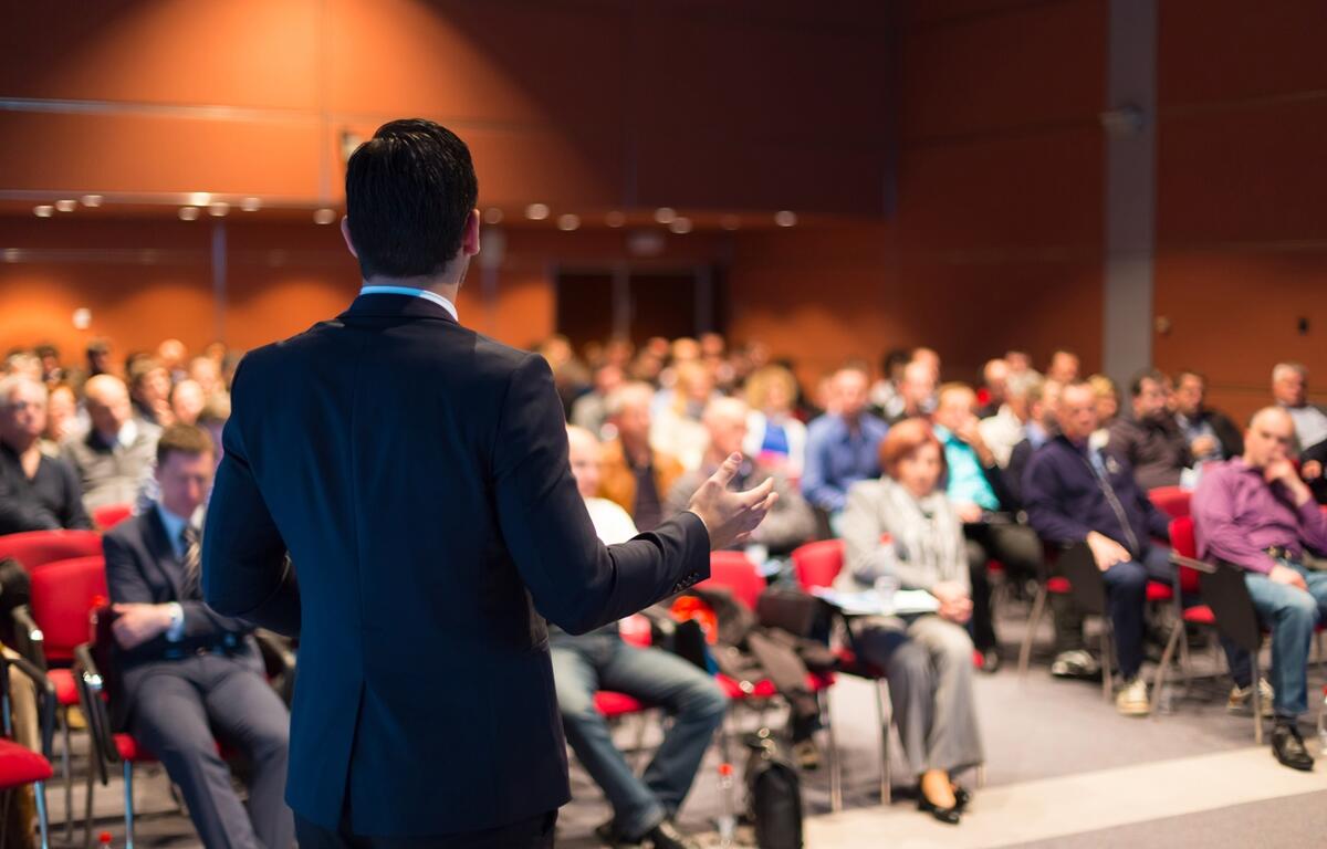 Man speaking to audience at a community meeting in a conference room