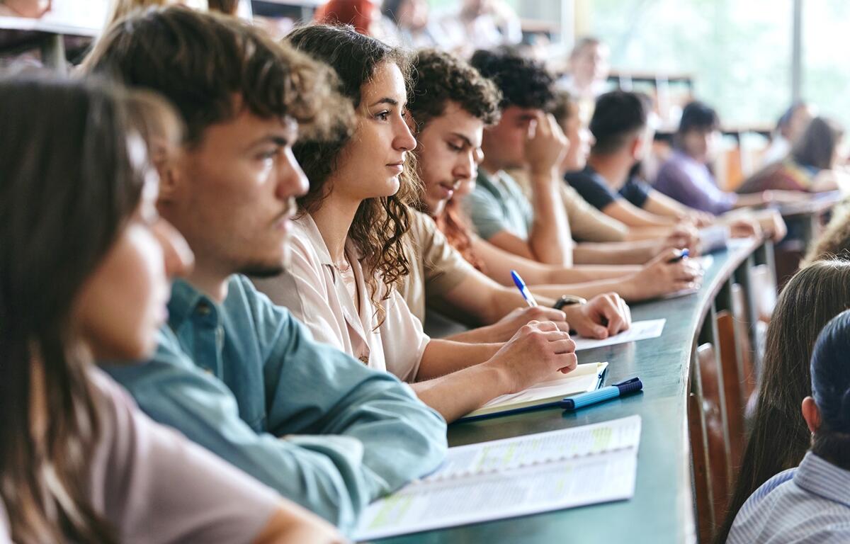 Students seated in a lecture hall taking notes during class.