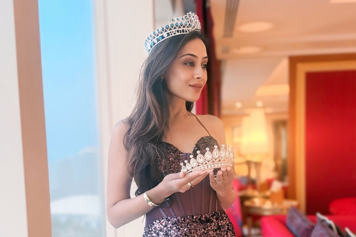 Nilam Patel wearing a crown and holding another in a hotel suite after Mrs. India Worldwide pageant in Dubai.