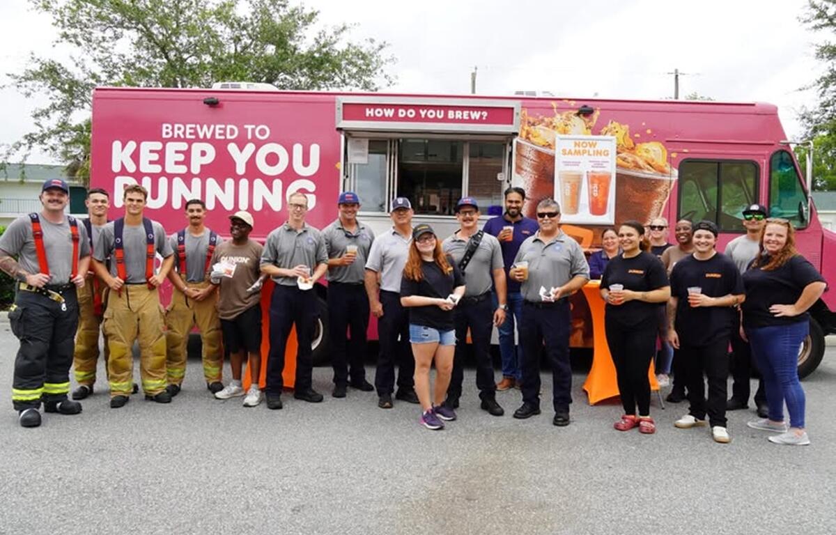 Ocala firefighters and Dunkin’ employees pose in front of the Dunkin’ Community Cruiser with drinks and treats.