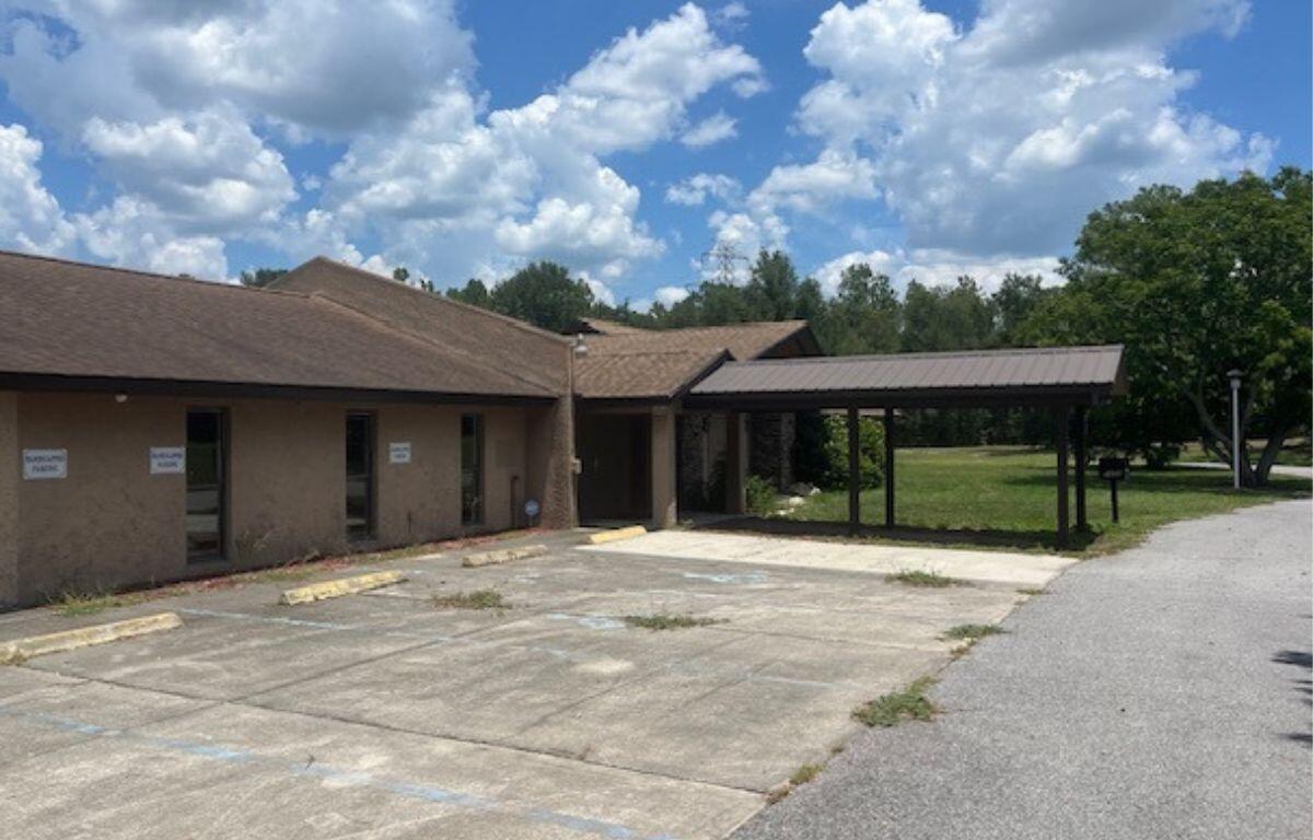 Exterior of former Elks Lodge building in Belleview with paved parking area and carport.