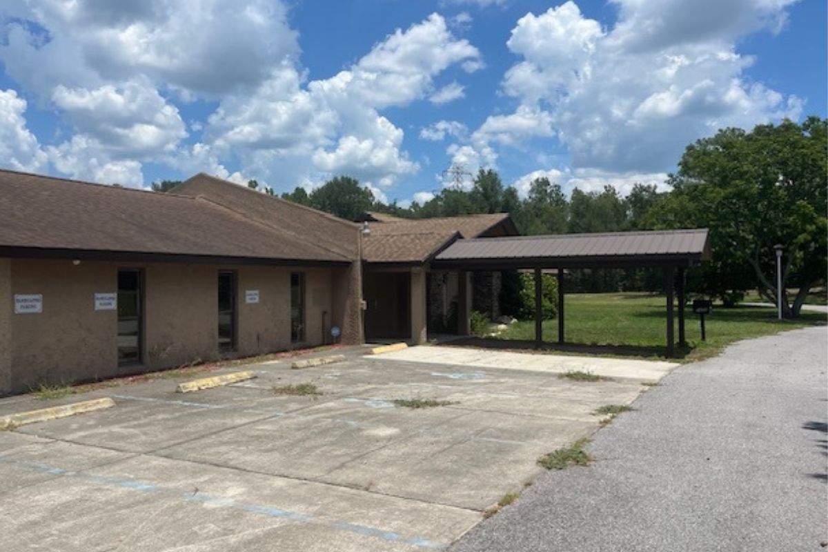 Exterior of former Elks Lodge building in Belleview with paved parking area and carport.