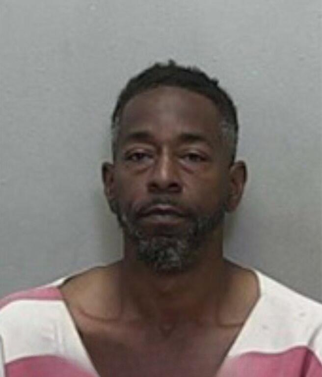 Mugshot of a man with short hair, wearing a red-and-white striped jail uniform.