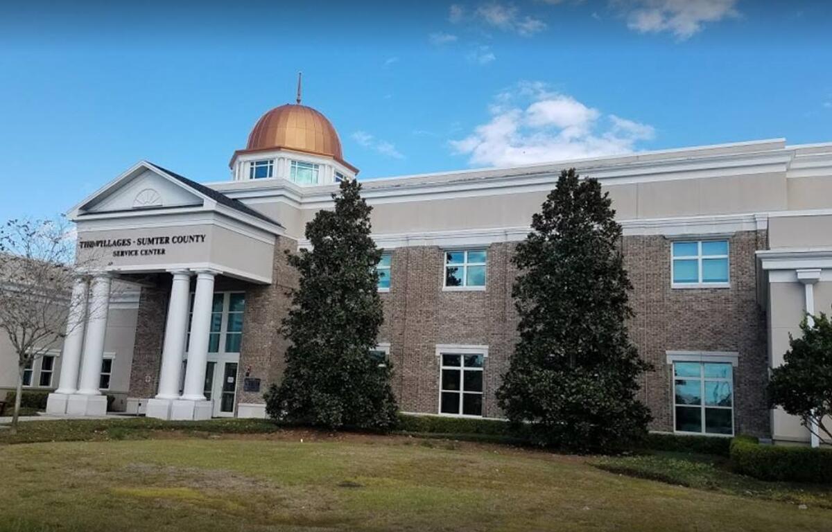 The Villages-Sumter County Service Center building with white columns and a copper dome under a blue sky.