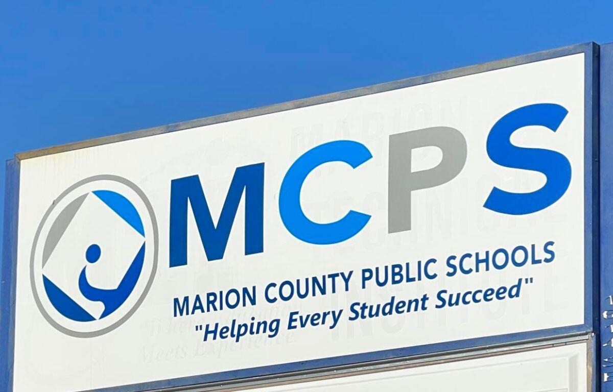 White sign with multi-colored lettering against the background of a blue sky