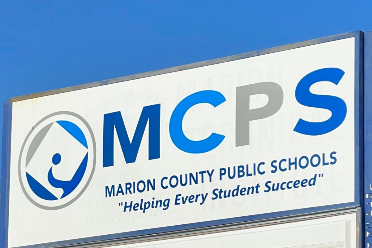 White sign with multi-colored lettering against the background of a blue sky