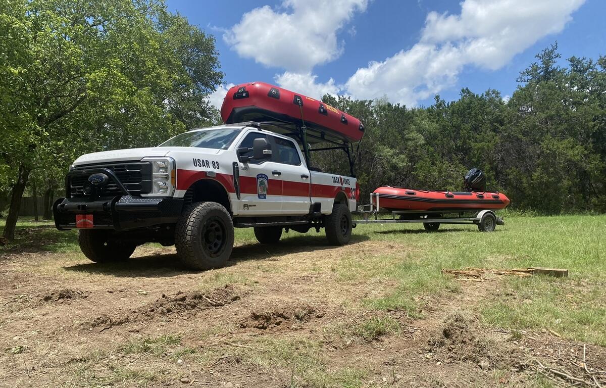 Task Force 8 rescue truck with inflatable boats parked on grass in Texas during flood deployment.