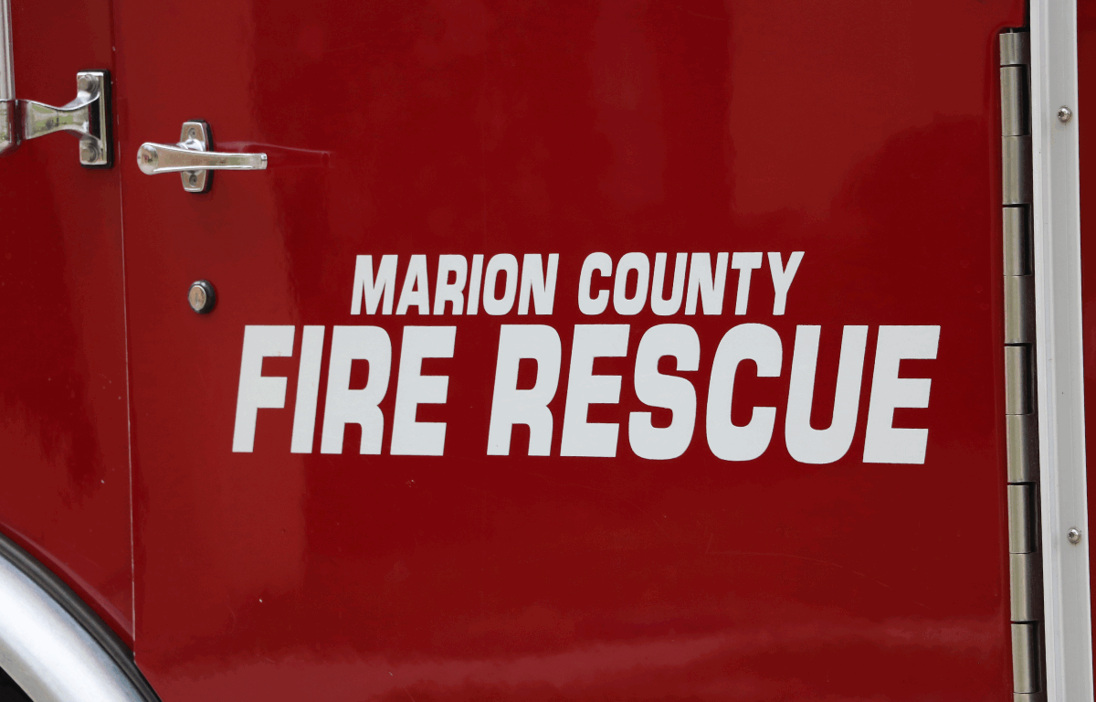 Close-up of "Marion County Fire Rescue" printed on a fire truck over a red background.