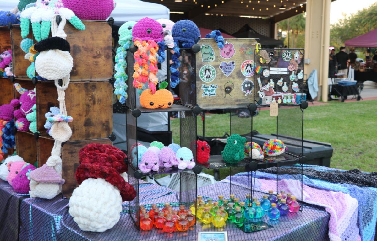 A table covered with yarn creations, including stuffed animals and doilies in vibrant shades.