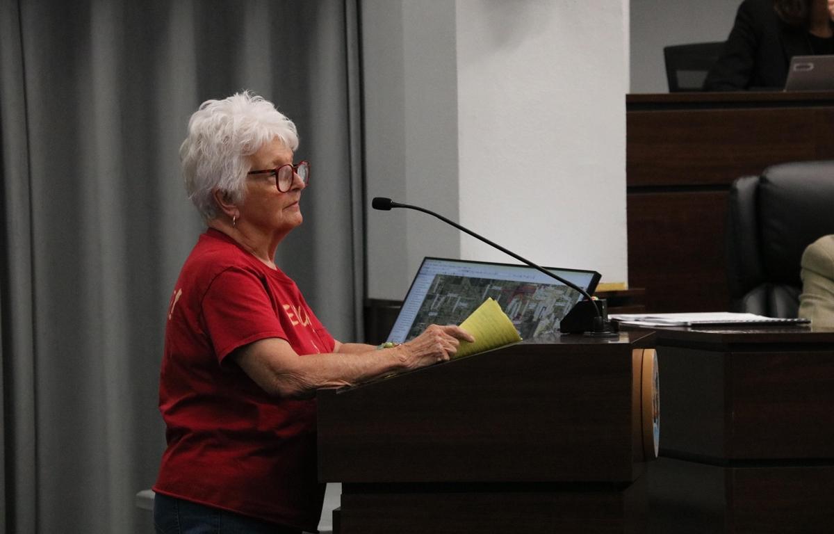 Woman in red shirt speaks at podium during Marion County Commission hearing.