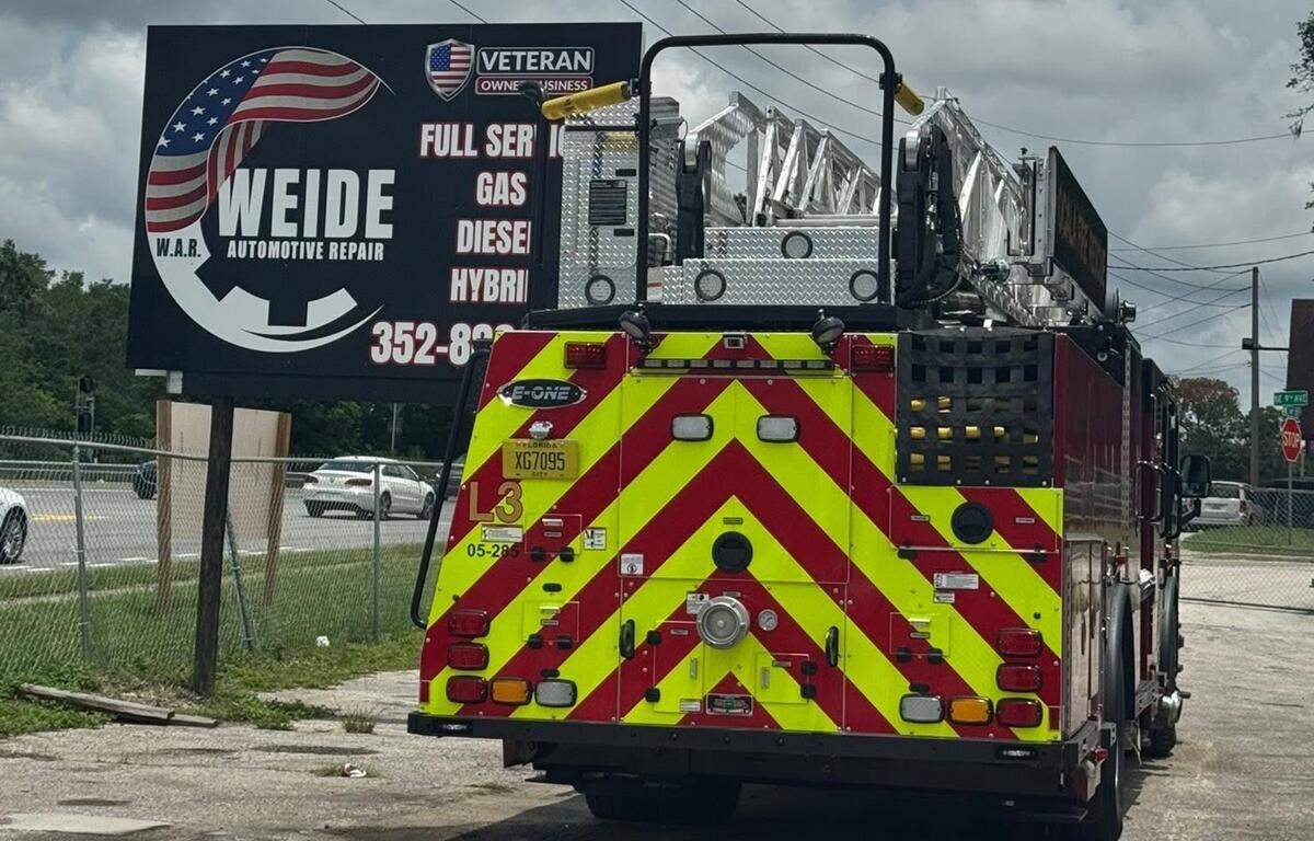Ocala Fire Rescue ladder truck parked near Weide Automotive Repair sign during training