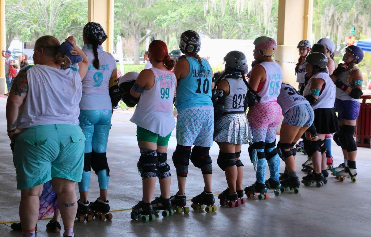 Line of skaters in mermaid colors standing in formation.