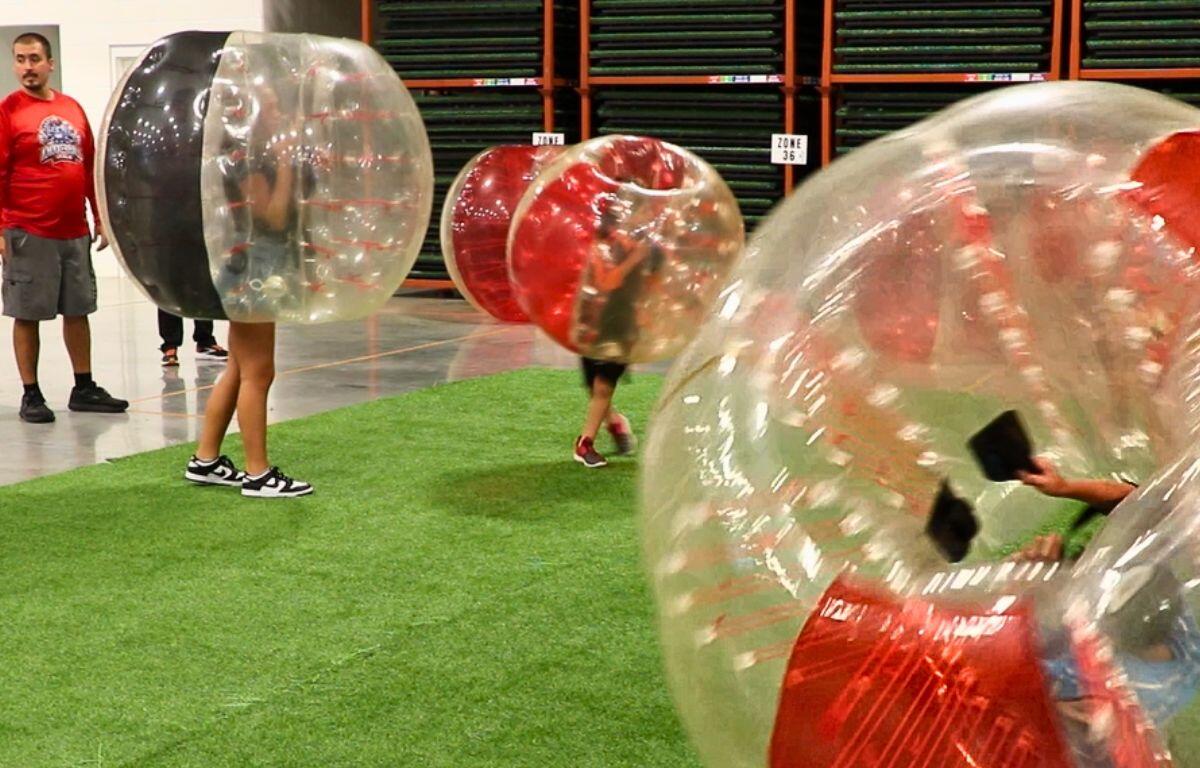 A green synthetic turf mat acts as an arena for different colored inflatable balls.