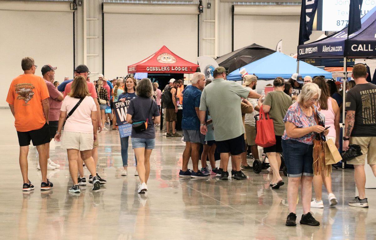 Wide shot of attendees walking through the expo floor lined with booths and activities.