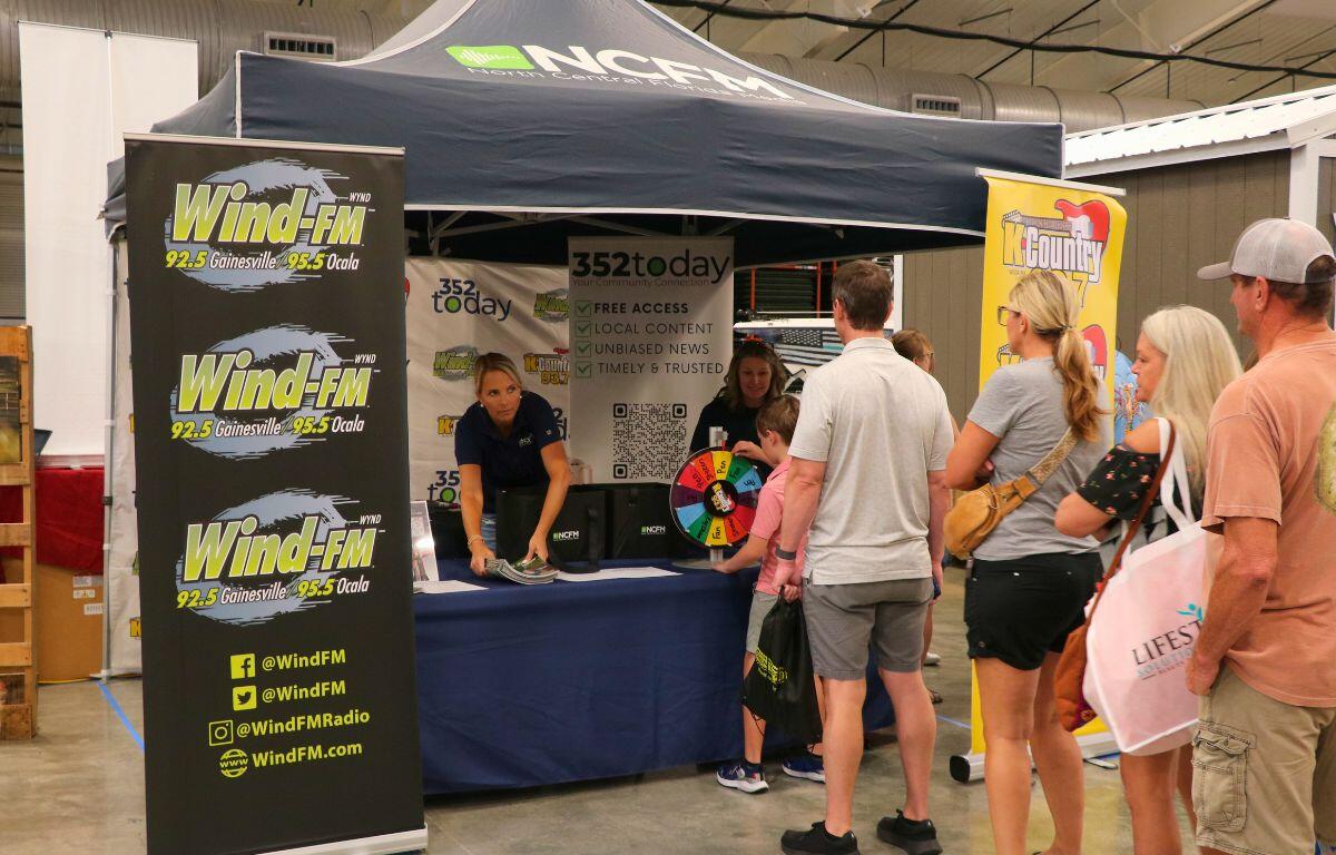 Group of attendees browsing tables and displays inside the expo hall.