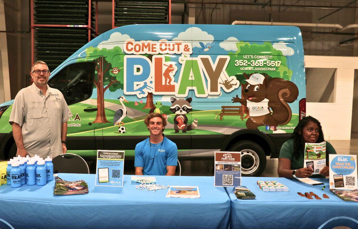 Vendor booth display with promotional banners and staff speaking with attendees.