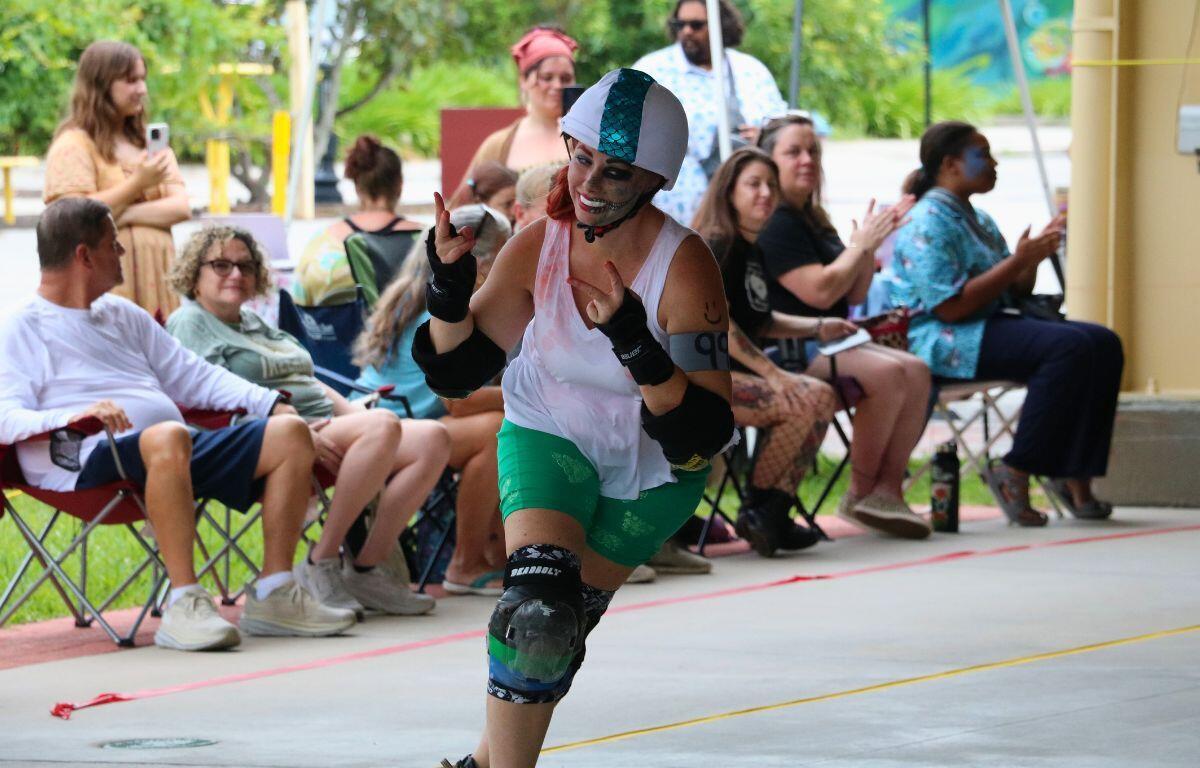 A skater from the Mermaids team accelerates past the sideline crowd.