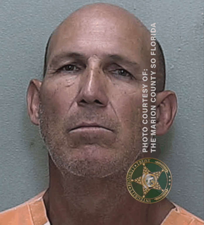 Mugshot of a bald man wearing an orange-and-white jail uniform, facing forward against a neutral background.