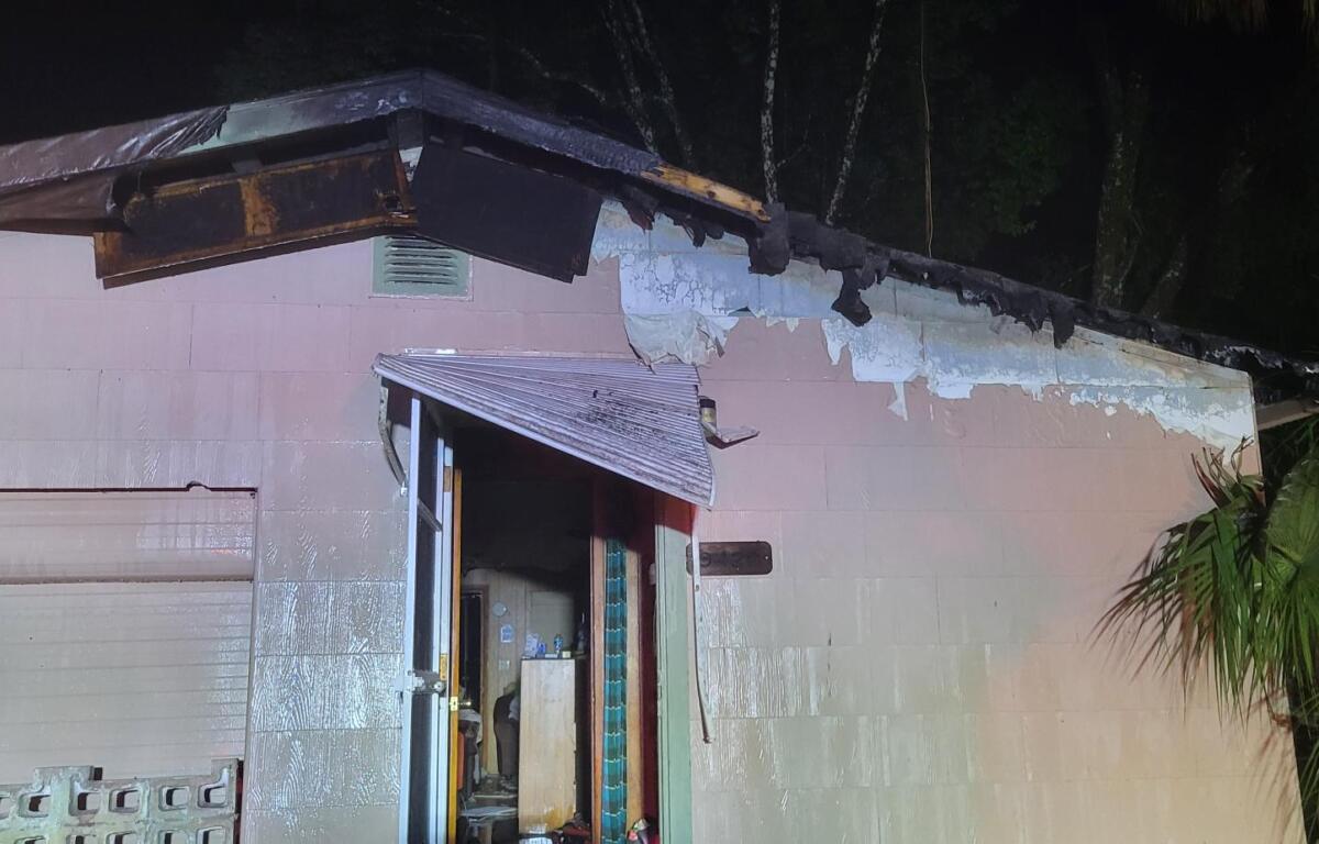 A house whose trim and front attic were damaged by a lightning Strike, scarred walls and an open door.