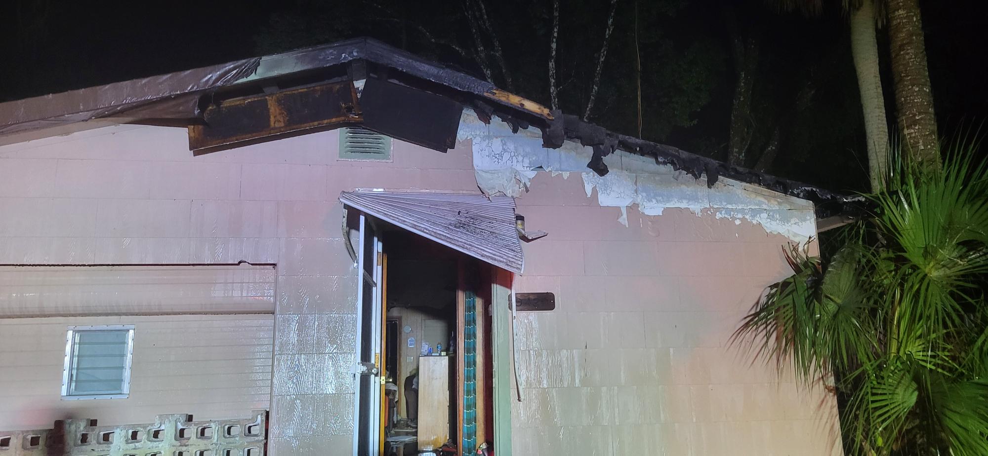 A house whose trim and front attic were damaged by a lightning Strike, scarred walls and an open door.