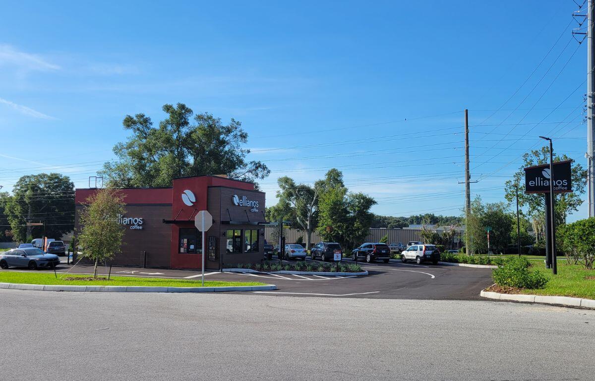 Ellianos Coffee's new drive-thru location on SW 60th Avenue in Ocala, featuring the building, parking lot, and roadside sign under a clear blue sky.