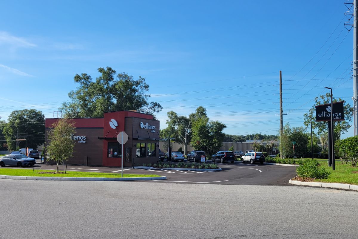 Ellianos Coffee's new drive-thru location on SW 60th Avenue in Ocala, featuring the building, parking lot, and roadside sign under a clear blue sky.