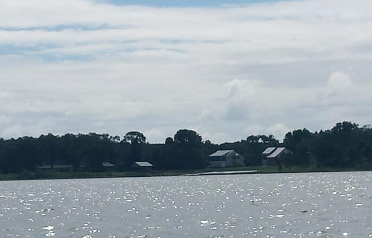 View of Lake Weir with houses and trees along the shoreline under a partly cloudy sky
